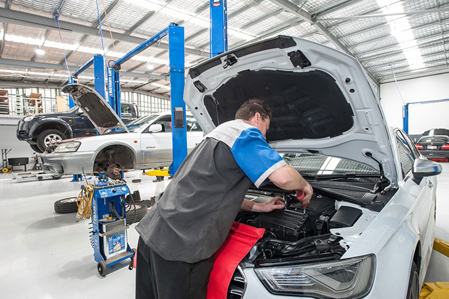 Technician repairing the machine of the white audi car