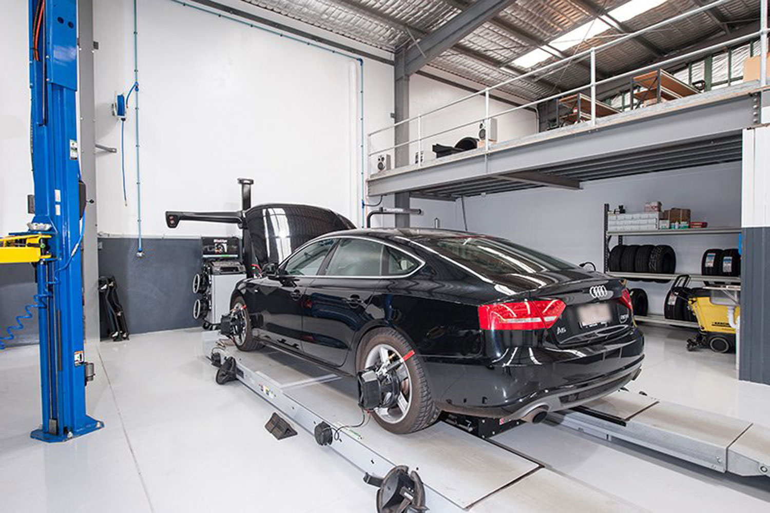 A black Audi car with open hood ready to be diagnose inside the workshop